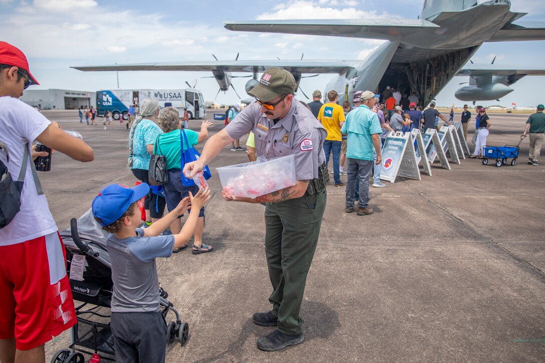 Zach Stafford, Park Ranger with the Galveston District, U.S. Army Corps of Engineers (USACE), hands out water safety whistles to visitors of the Hurricane Hunter Aircraft display at Ellington Airport.