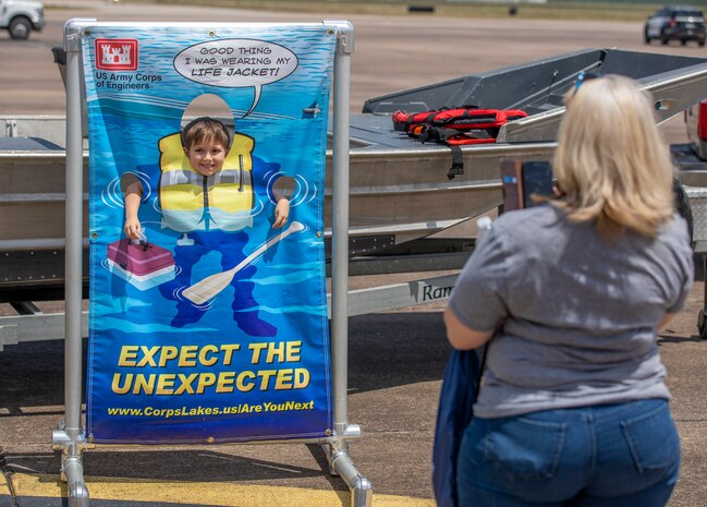A child poses with a water safety banner from the Galveston District, U.S. Army Corps of Engineers (USACE), during the Hurricane Hunter Aircraft display at Ellington Airport.