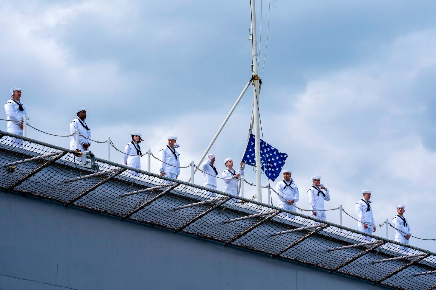 A Sailor aboard the capital ship of the Gerald R. Ford Carrier Strike Group (GRFCSG), the first-in-class aircraft carrier USS Gerald R. Ford (CVN 78), lowers the Union Jack prior to departing Naval Station Norfolk for a routine deployment, May 2.