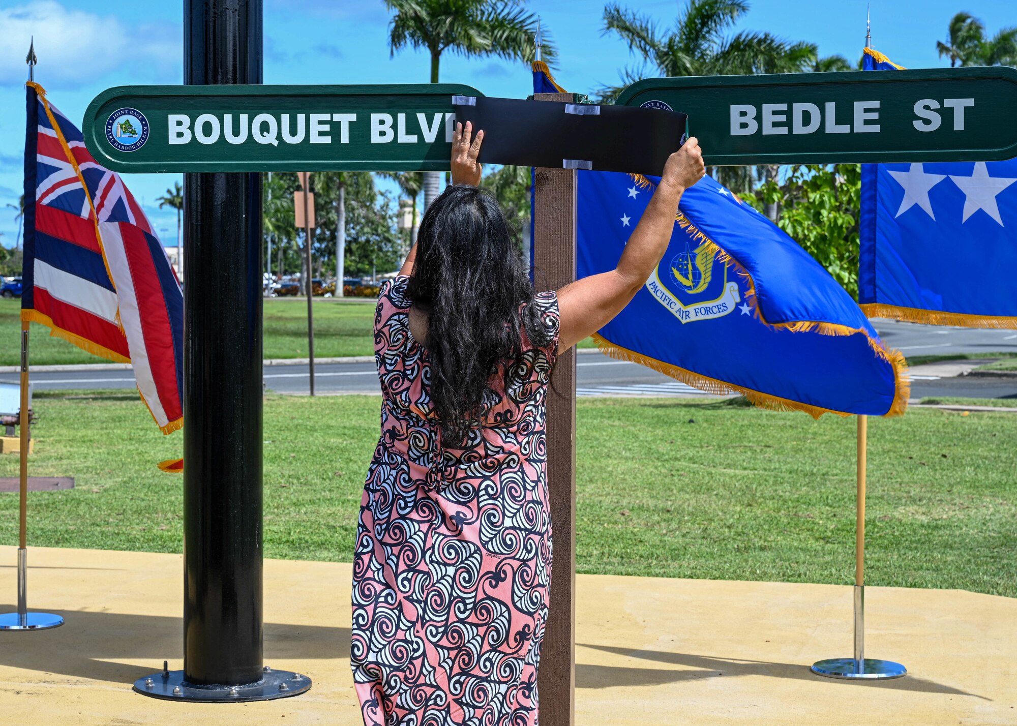Jessie Higa, 15th Wing local historian, removes the incorrect spelling of “Bouquet Blvd” during a rededication ceremony at Joint Base Pearl Harbor-Hickam, Hawaii, April 26, 2023.