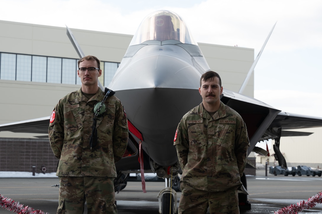 A photo of two Airmen standing in front of an F-22