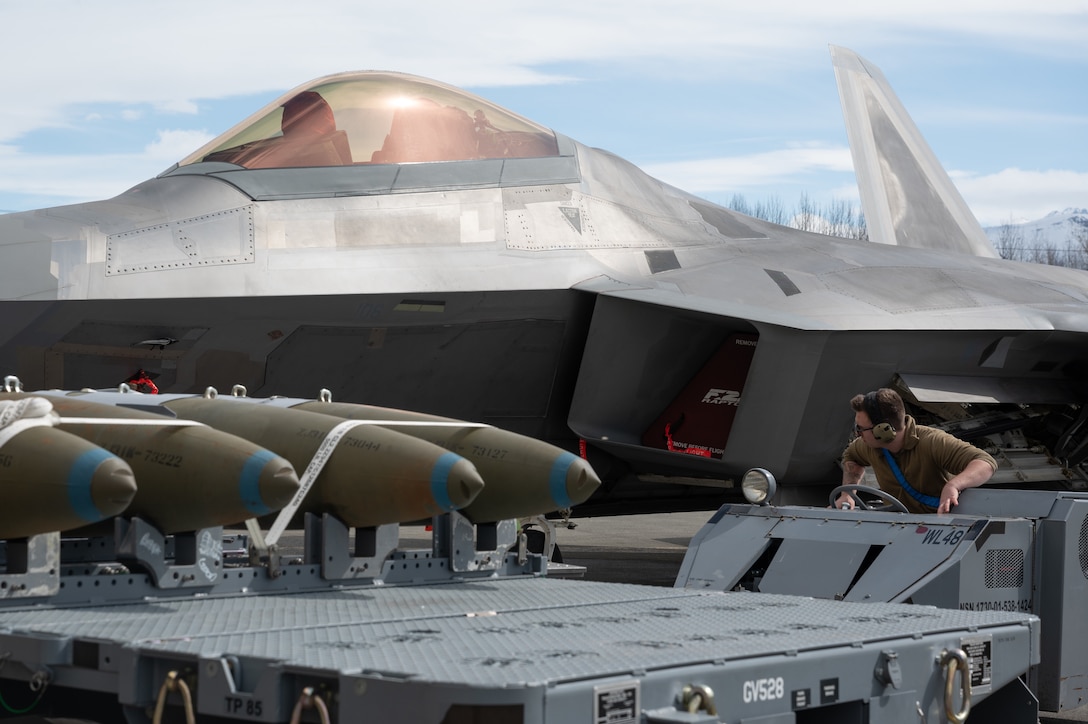 A photo of an Airman loading bombs onto an F-22