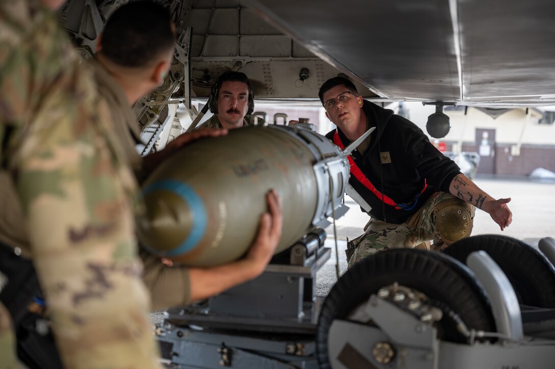 A photo of Airmen guiding a bomb into an F-22