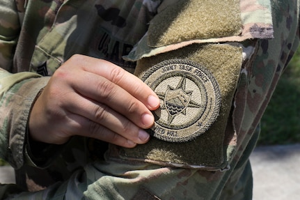 A U.S. Army Soldier assigned Joint Task Force-Red Hill (JTF-RH) attaches a unit patch to her uniform at a patching ceremony at task force headquarters on Ford Island, Hawaii, April 28, 2023.