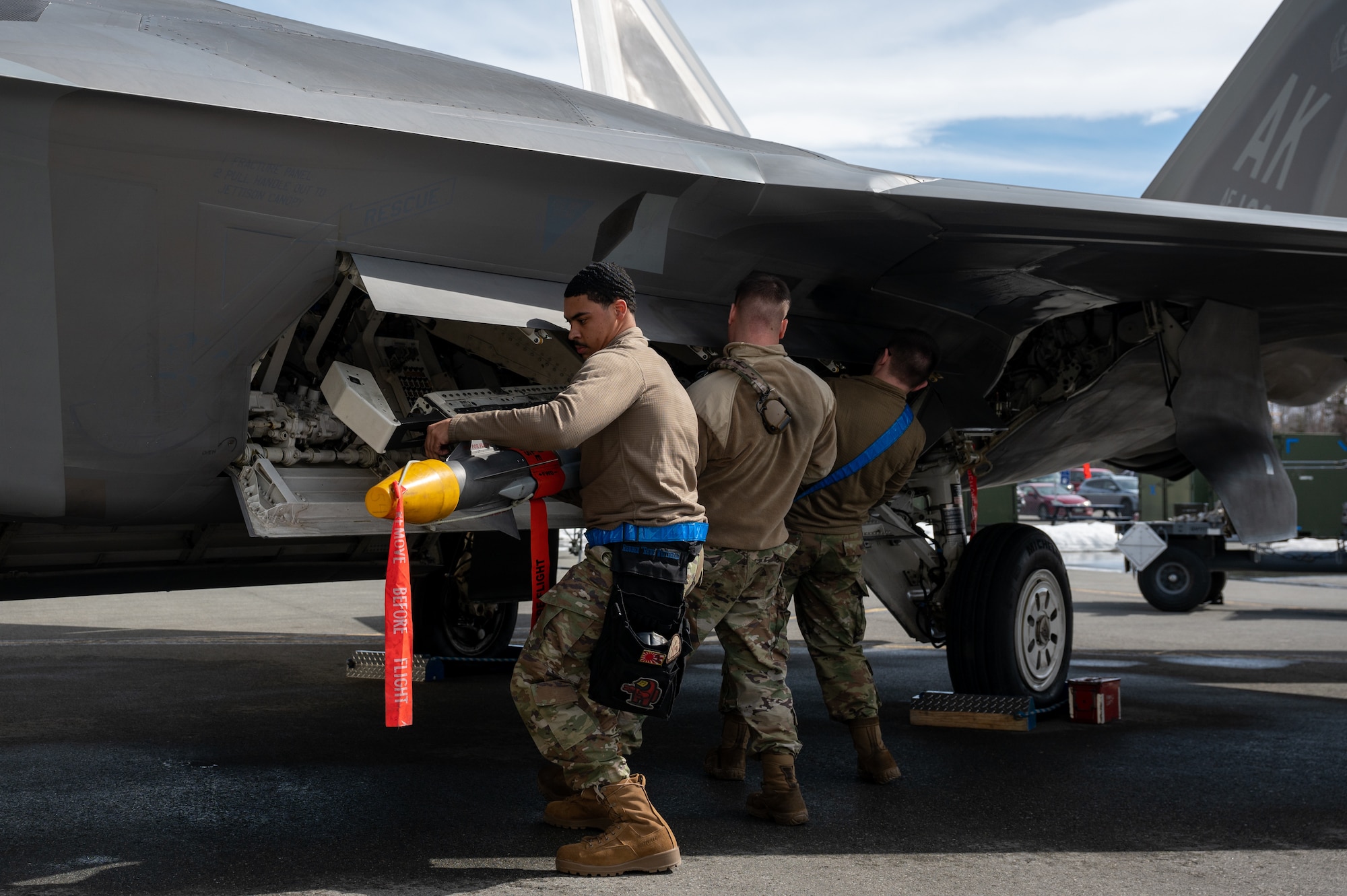A photo of Airmen loading a missile onto a F-22