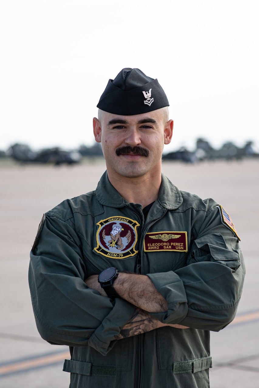 Sailor posing with arms crossed smiling at camera on the flightline