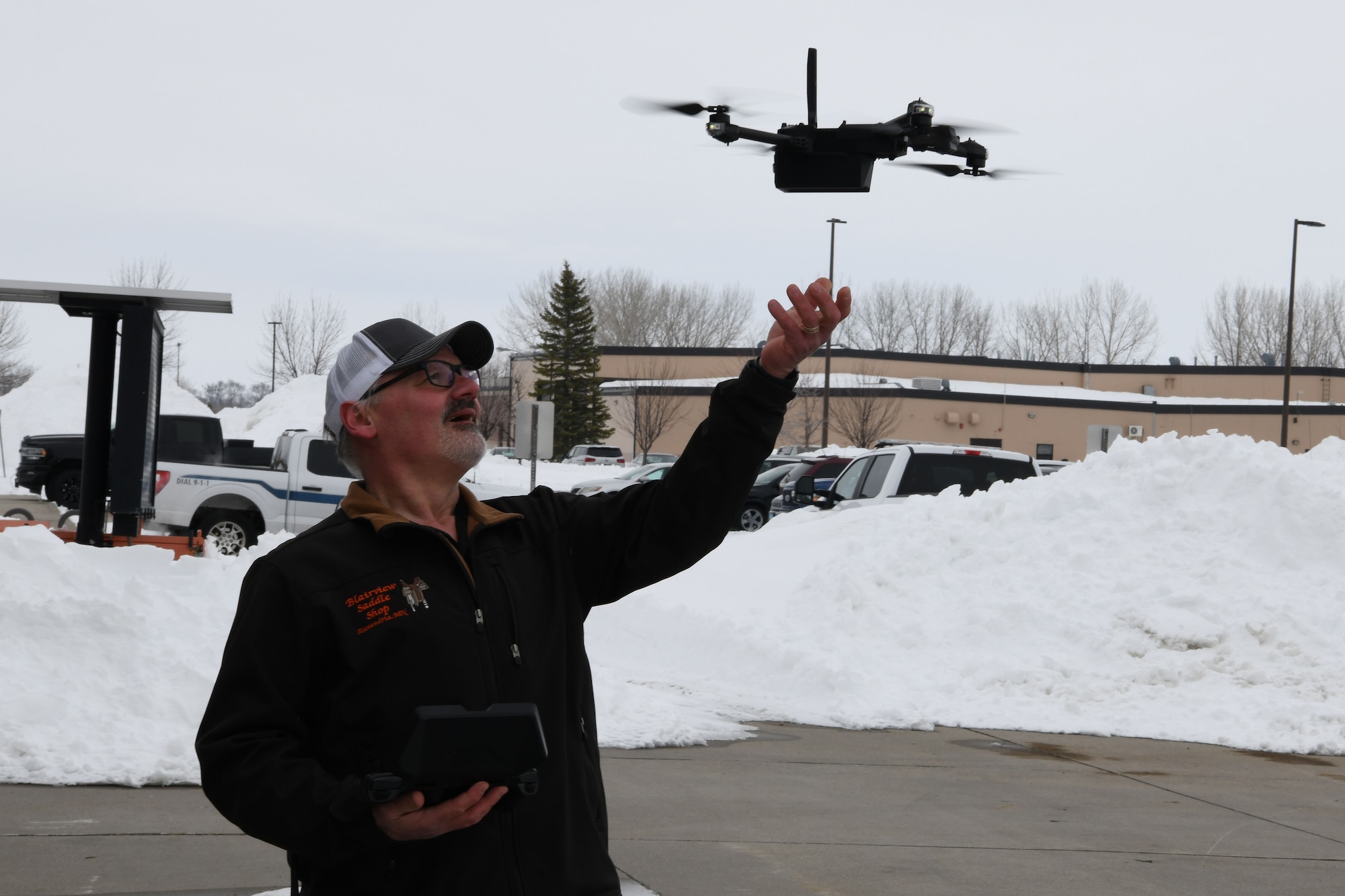 Man in black jacket catches reaches for flying drone.