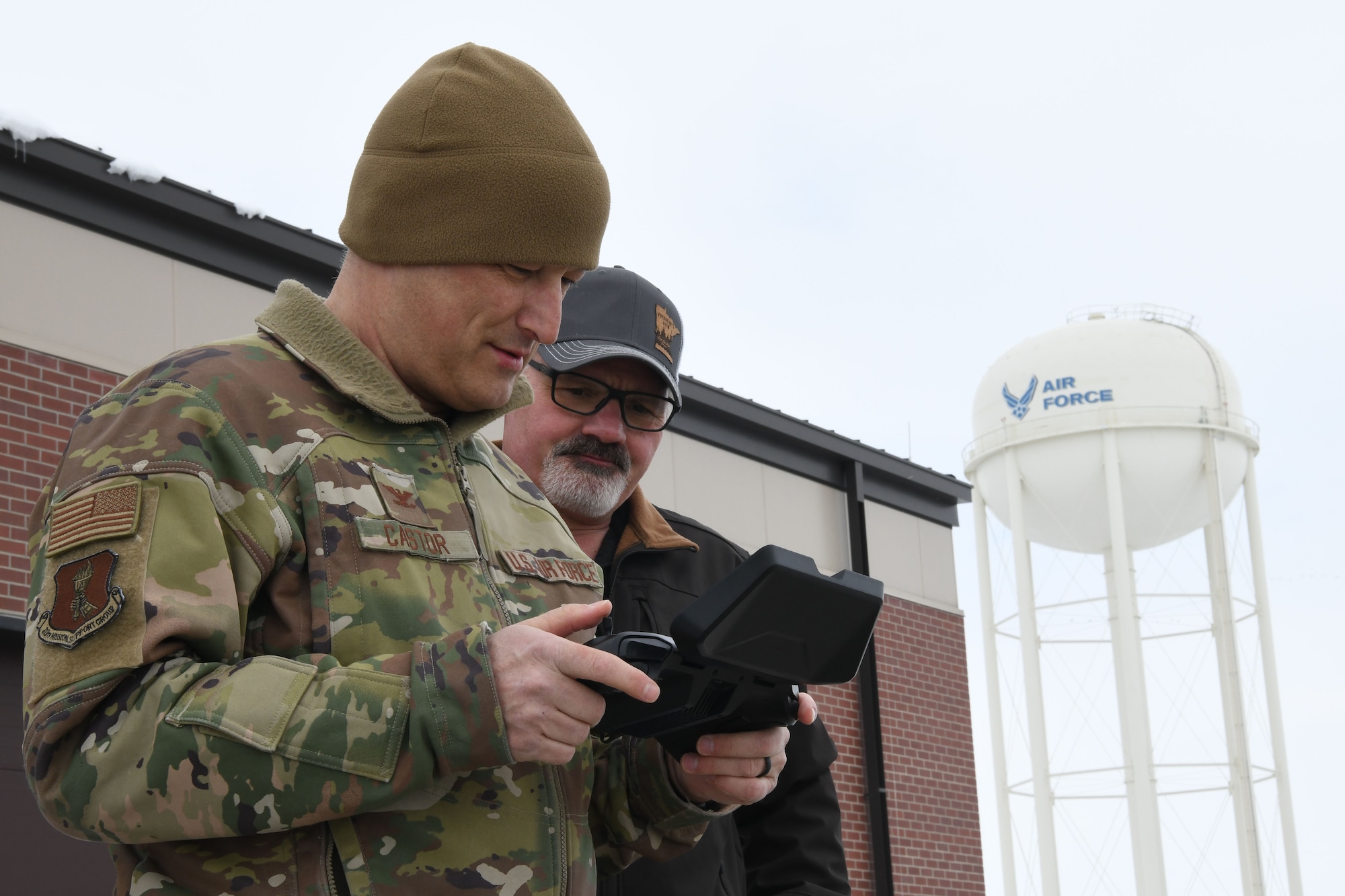 Man in green uniform looks at remote control