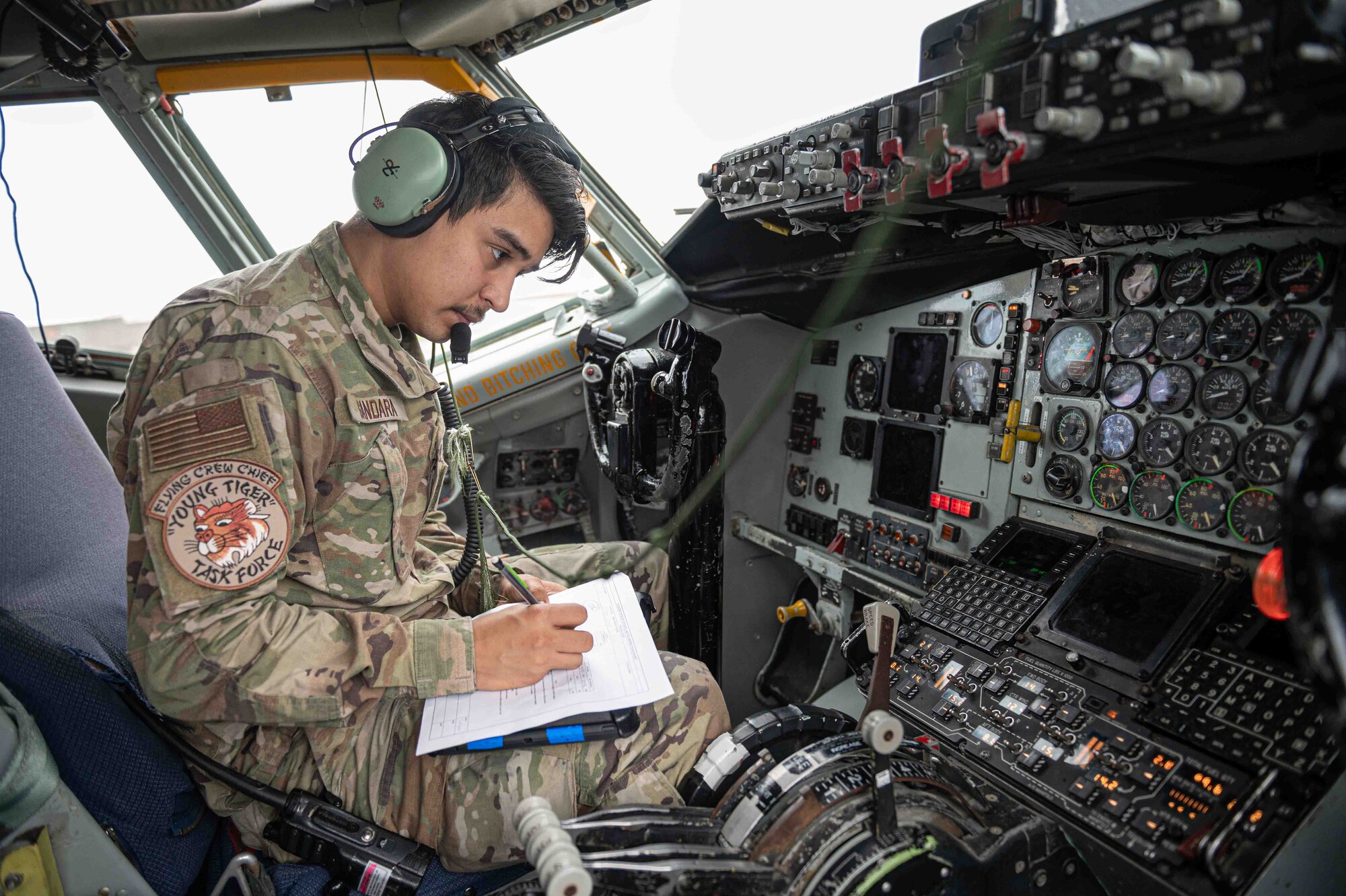 Airman sits in the cockpit of an aircraft writing down fuel levels