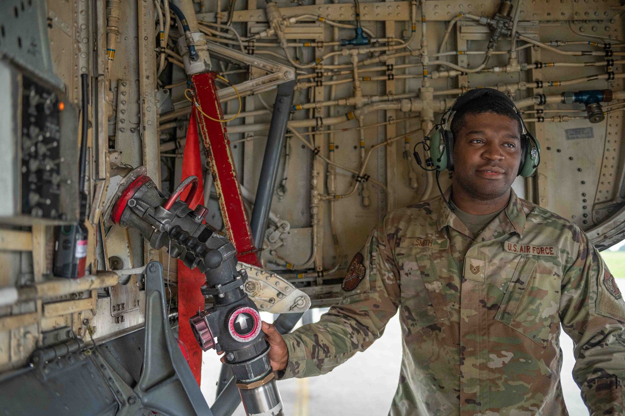 Airman holds a fuel hose up to an aircraft
