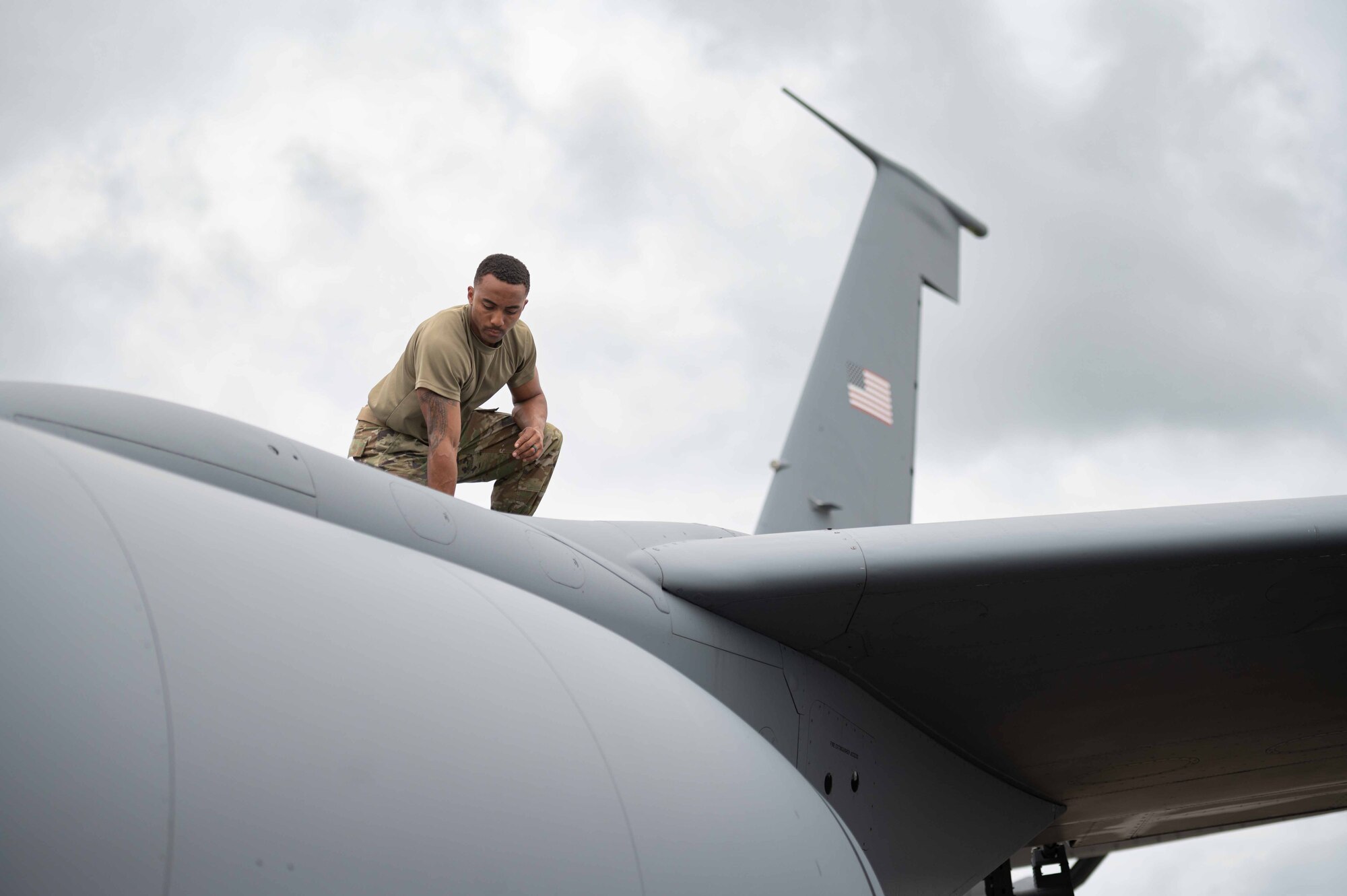 Airman inspects the top of an aircraft