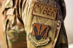 Patches on the sleeve of a military uniform say “cyber” and “Air Combat Command.”