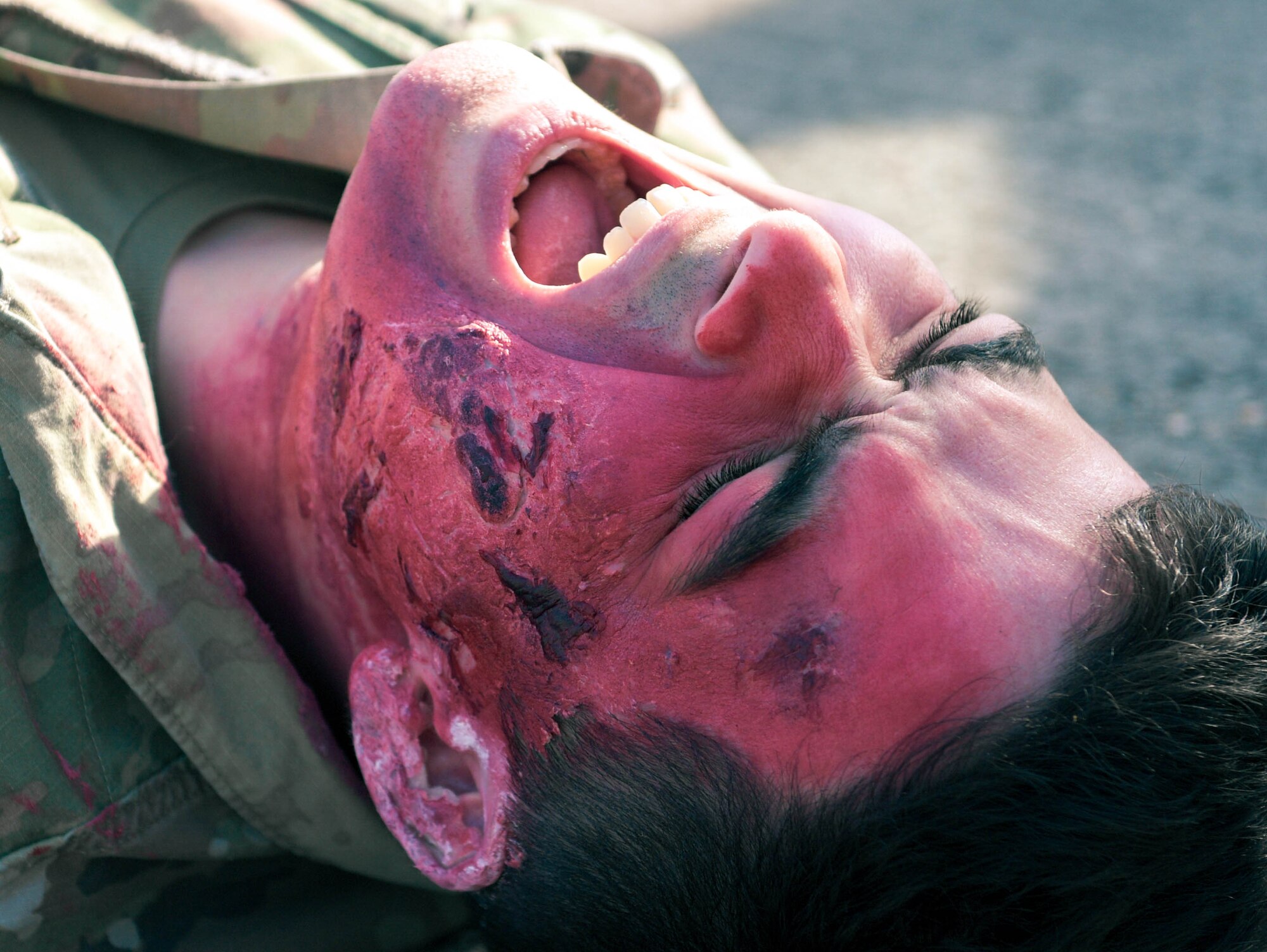 U.S. Air Force Airman 1st Class Austin Irving, exercise volunteer, pretends to scream in pain from his simulated injury during exercise Ready Eagle II at Ramstein Air Base, Germany, April 27, 2023. The Kaiserslautern Military Community Fire and Emergency Services firefighters evacuated volunteers from the hangar during the scenario and assessed their injuries to provide emergency medical care. Instructors evaluated personnel on their ability to respond to a variety of medical conditions.