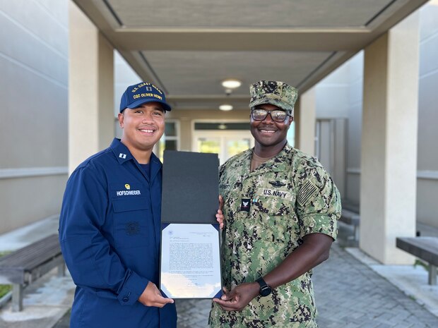 Lt. Freddy Hofschneider, commanding officer of USCGC Oliver Henry (WPC 1140), presents a U.S. Coast Guard Letter of Commendation to Petty Officer 3rd Class Christopher Hardnett on behalf of Capt. Nick Simmons, commander of U.S. Coast Guard Forces Micronesia/Sector Guam, at an all-hands ceremony on Navy Base Guam at the new Branch Medical Clinic on April 27, 2023. Hardnett provided medical support for the Oliver Henry's 43-day expeditionary patrol in 2022. (U.S. Coast Guard photo by Lt. j.g. Marissa Marsh)