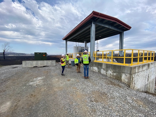 People stand in front of a pump station