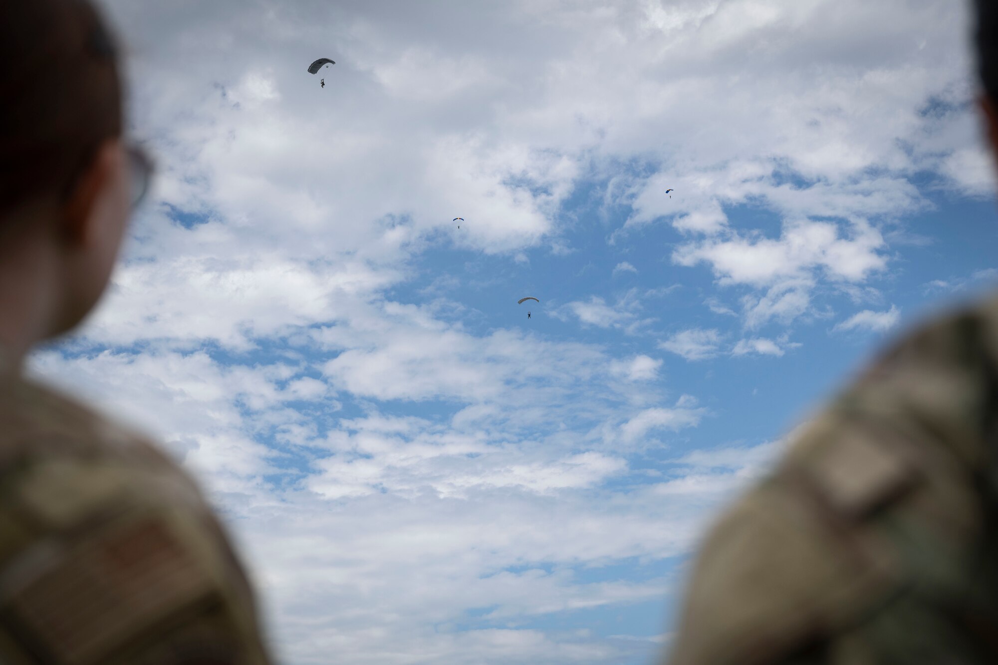 U.S. Air Force Senior Airman Samantha Gibson, right, and Airman 1st Class Jayden Baker, 4th Operations Support Squadron weather journeymen, are watching members of the Belgian Special Operations Regiment executing military free fall during exercise Southern Strike near Gulfport Mississippi, April 24, 2023. Southern Strike promotes interoperability between special forces, conventional ground forces and air assets to ensure the U.S. military stays relevant and ready to respond to a peer-to-peer large scale combat operation.