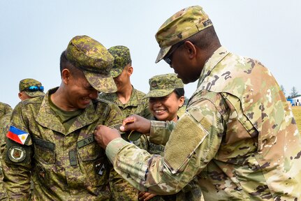 U.S. Army 1st Sgt. Tim Morgan with the Mississippi Army National Guard’s Bravo Battery, 1st Battalion, 204th Air Defense Artillery Regiment, gives a patch to a member of the Philippine Armed Forces in San Narciso, Philippines April 22 during Exercise Balikatan 2023. The Mississippi Guard Soldiers were among 17,600 service members from the Armed Forces of the Philippines, U.S. Marine Corps, Navy, Air Force, Army, Coast Guard and special operations forces, marking the largest iteration in the exercise’s history.