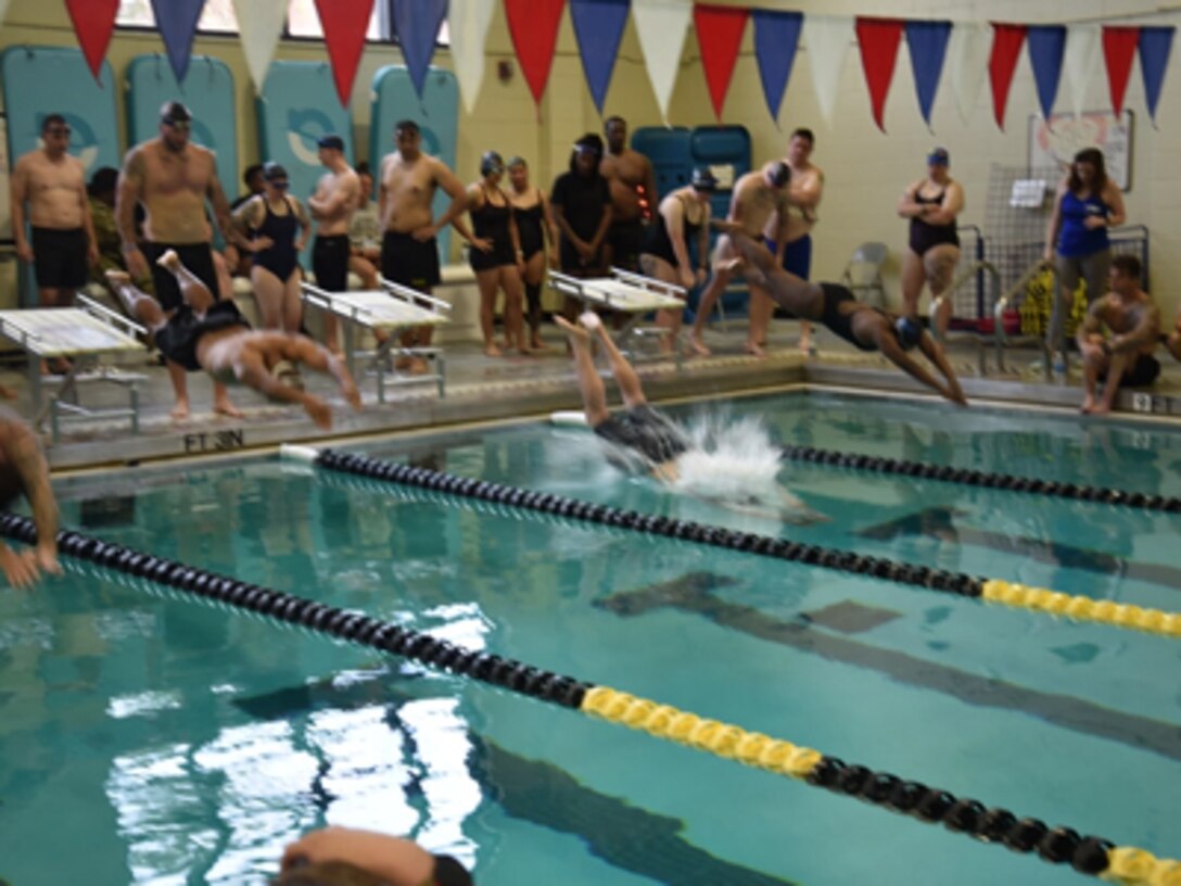 U.S. Army Staff Sgt. Obed Lebron (second from left) dives during training while athlete mentor, program alum, and Invictus Games competitor Ross Alewine looks on. U.S. Army Adaptive Sports Camp at Fort Bragg, North Carolina, March 31, 2023.Over 70 wounded, ill and injured Soldiers are training in a series of athletic events including archery, cycling, shooting, sitting volleyball, swimming, powerlifting, track, field, rowing, and wheelchair basketball. The Adaptive Sports Camp celebrates wounded, ill, and injured Soldiers' ability to recover and overcome. The Army holds qualifying trials for Active Duty, wounded, ill or injured Soldiers to assess and select athletes for competition in the Warrior Games Challenge. This year, the DoD Warrior Games Challenge takes place in June 2023 at Naval Air Station North Island in San Diego, California. (DOD photo by Keisha Frith)