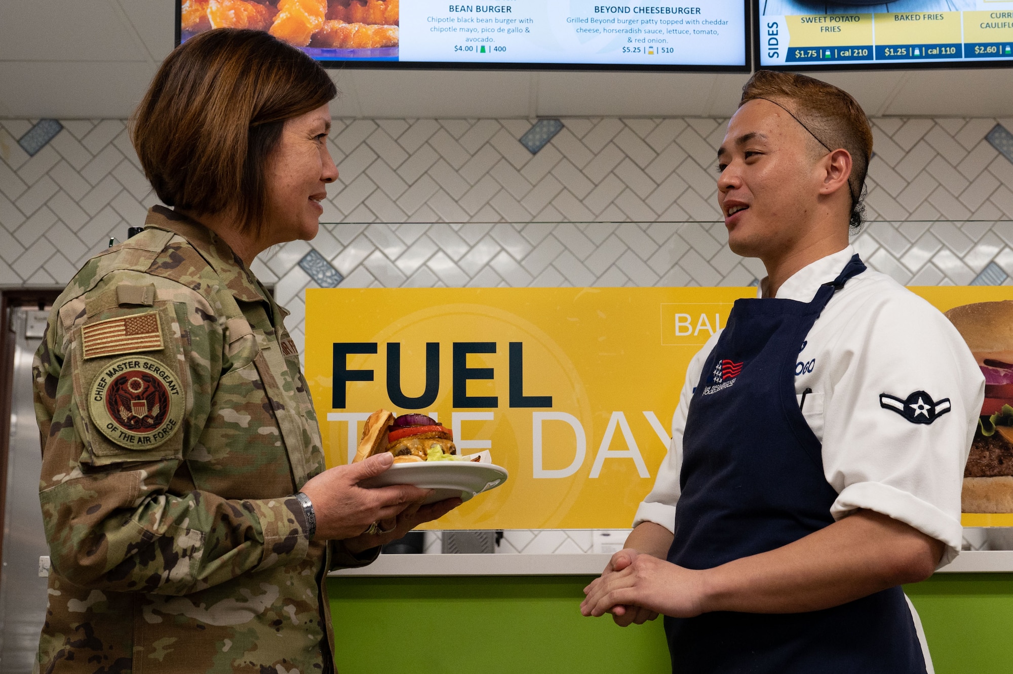 Chief Master Sgt. of the Air Force JoAnne S. Bass, left, gets introduced to Airman Gary Quinata Ogo, 99th Force Support Squadron food service specialist, during a visit at Nellis Air Force Base, Nevada, May 2, 2023.