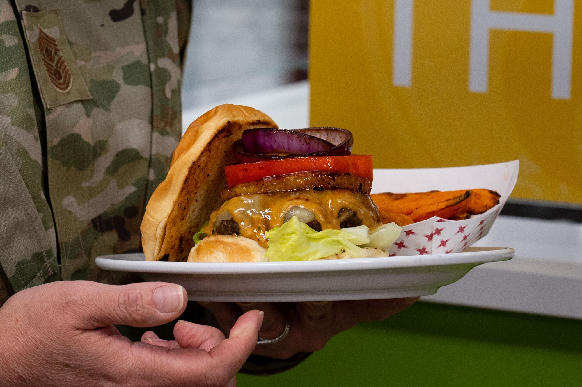 Chief Master Sgt. of the Air Force JoAnne S. Bass, receives an Airman’s signature burger, during a visit at Nellis Air Force Base, Nevada, May 2, 2023.
