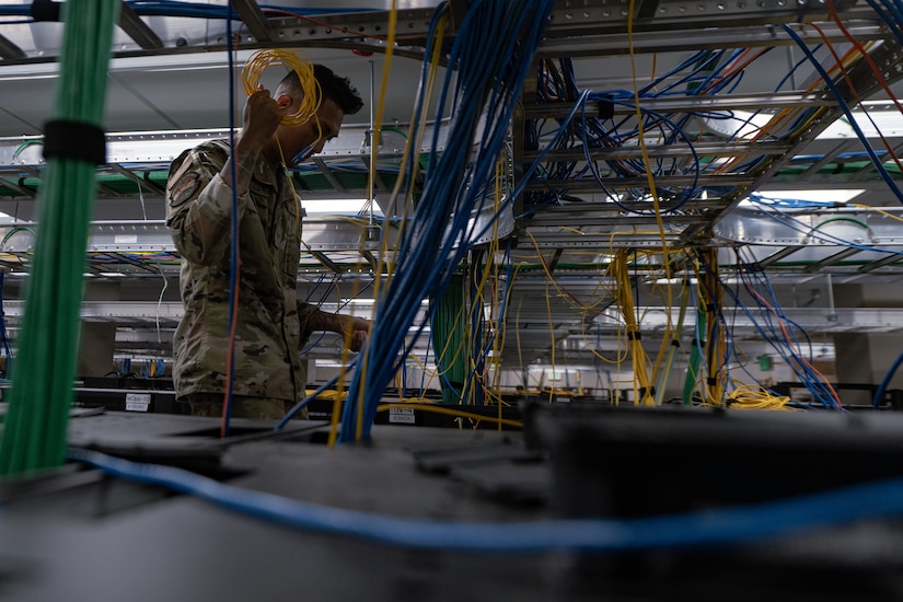 A service member handles computer network wiring.