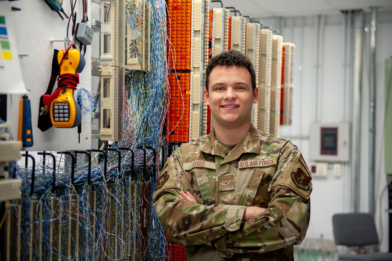 A service member poses next to information technology hardware.