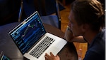 Image of an individual focused on charts and data on a laptop.