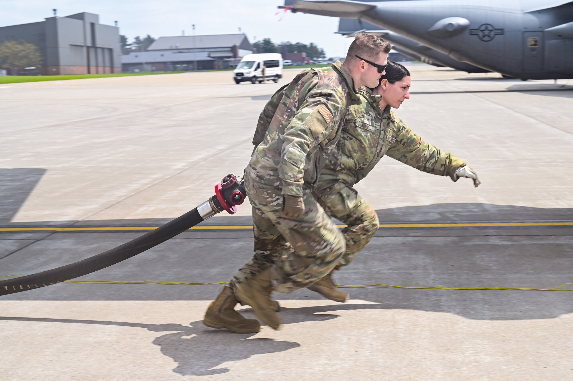Tech. Sgt. Taylor Creston, an aerospace maintenance specialist assigned to the 910th Maintenance Squadron, and Senior Airman Victoria Russo, a fuels specialist assigned to the 910th Logistics Readiness Squadron, pull a fuel hose to a C-130H Hercules aircraft on April 25, 2023, at Youngstown Air Reserve Station, Ohio.