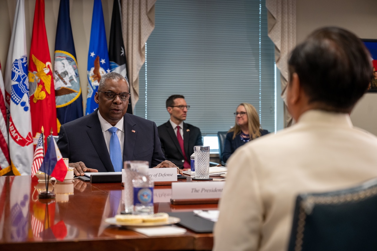 Secretary of Defense Lloyd J. Austin III speaks with Philippine President Ferdinand Marcos at a table.