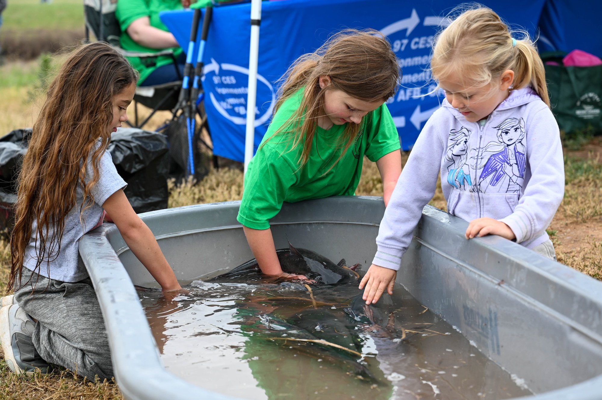 Children touch live catfish that were caught at the 97th Civil Engineer Squadron environmental flight’s annual fishing derby at the base pond on Altus Air Force Base, Oklahoma, April, 28, 2023. The environmental team filled the pond with live catfish for the event. (U.S. Air Force photo by Airman 1st Class Heidi Bucins)