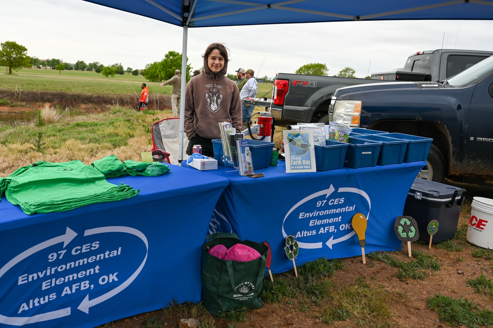 Molly Willoughbuy, 97th Civil Engineer Squadron (CES) environmental office intern, smiles for a photo while working at the 97th CES environmental flight's fishing derby at Altus Air Force Base, Oklahoma, April 28, 2023. Willoughbuy worked at a booth that offered merchandise to promote environmentally- safe products such as reusable drinking straws and shopping bags in honor of Earth Day. (U.S. Air Force photo by Airman 1st Class Heidi Bucins)