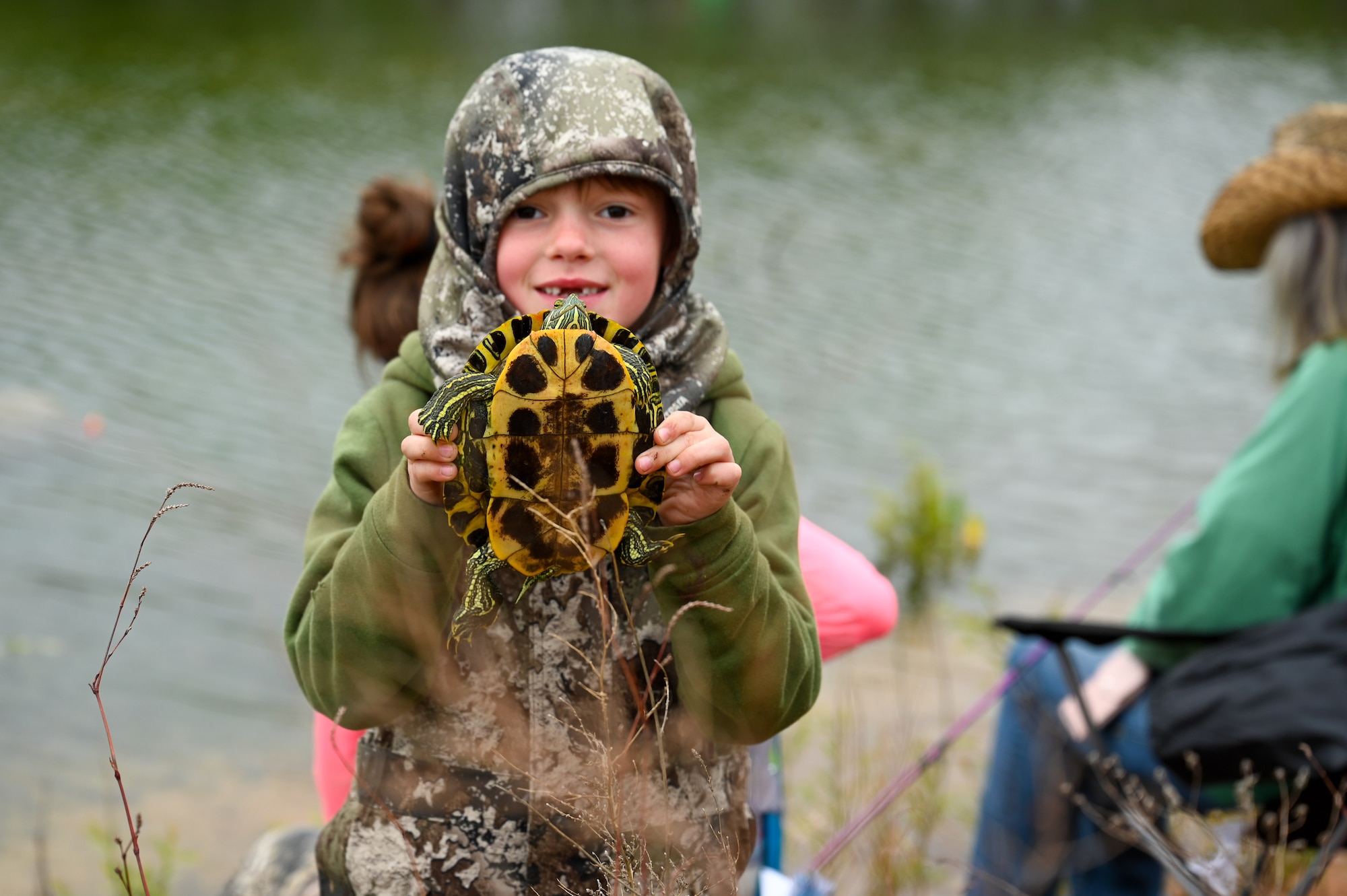 A child poses for a photo with a red-eared slider turtle he found at the base fishing pond during the 97th Civil Engineer Squadron environmental flight’s annual fishing derby event at Altus Air Force Base, Oklahoma, April 28, 2023. The fishing derby gave out a prize to the contestant who caught the largest fish. (U.S. Air Force photo by Airman 1st Class Heidi Bucins)