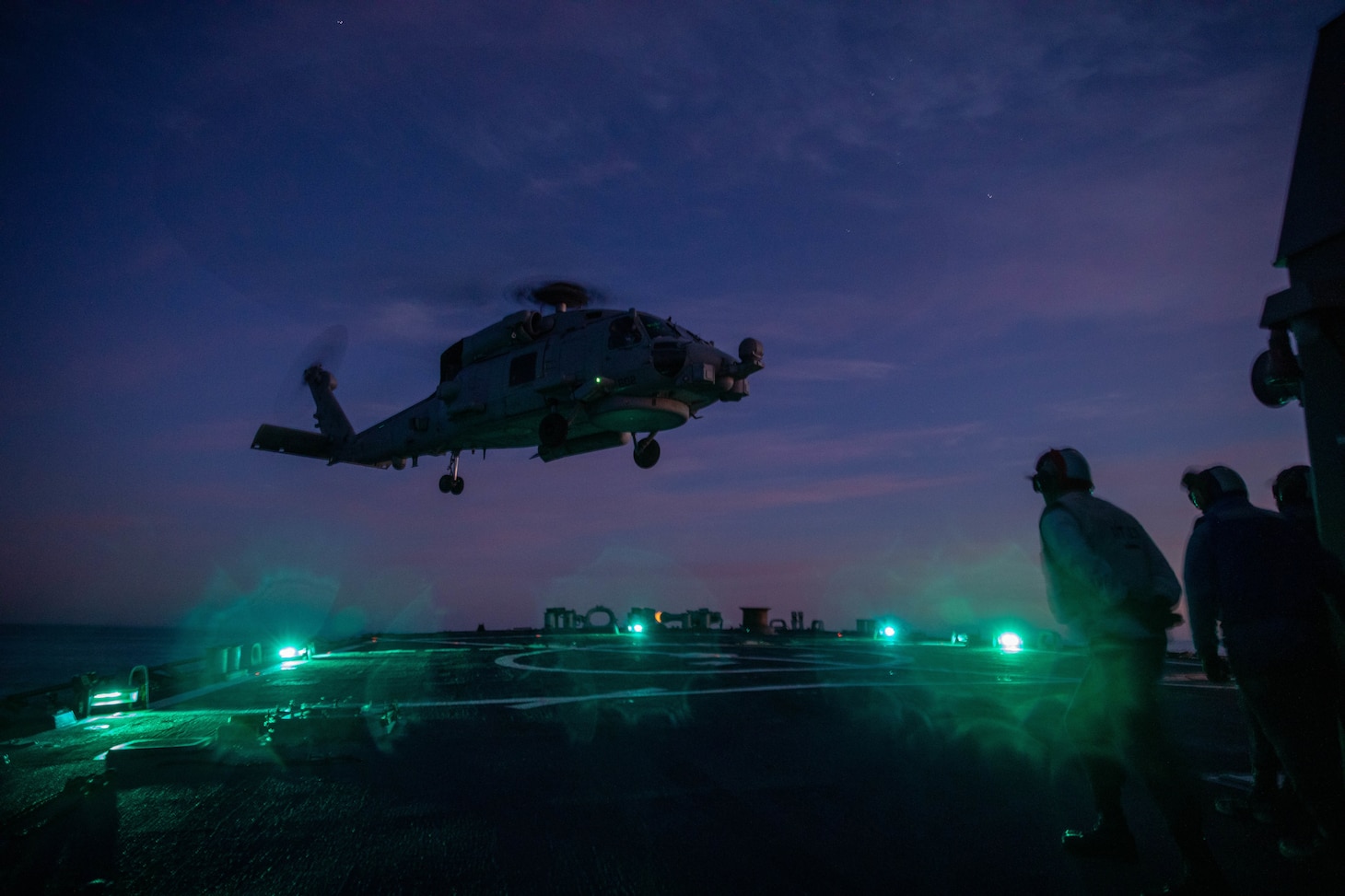 Sailors assigned to Arleigh Burke-class guided-missile destroyer USS Donald Cook (DDG 75) watch as an MH-60R Seahawk helicopter of the "Jaguars" of Helicopter Maritime Strike Squadron (HSM) 60 departs the flight deck, March 8.