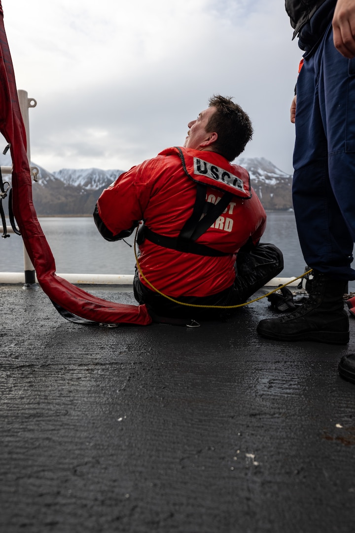 U.S. Coast Guard Fireman Mathew Coletta sits on the edge of U.S. Coast Guard Cutter Alex Haley during a port call in Dutch Harbor, Unalaska, Alaska, April 4, 2023. The Alex Haley crew
conducted cutter surface swimmer training to reinforce
proficiency in raising and lowering the swimmer and potential survivor from the water to the deck of the cutter for further care.