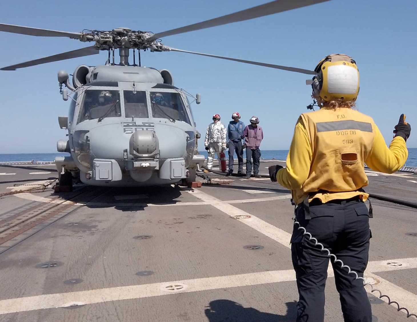 Boatswain’s Mate 3rd Class Jacqueline Husch directs flight deck operations as Landing Signals-Enlisted while MH60R “Jaguar 606”, attached to Helicopter Maritime Strike Squadron 60 (HSM 60), conducts refueling operations on the flight deck of Arleigh Burke-class guided-missile destroyer USS Forrest Sherman (DDG 98).