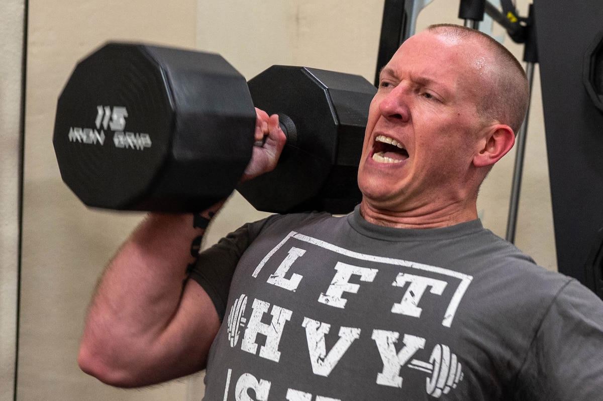 Master Sgt. Ryan Kelly, a 934th Maintenance Squadron flight chief, overhead presses a dumbbell for a strongman competition at the fitness center on Minneapolis-St. Paul Air Reserve Station, Minneapolis, on April 20, 2023. This is the first strongman competition held by the 934AW. (U.S. Air Force photo Chris Farley)