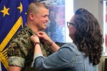 A marine has his new rank pinned on his collar by his wife.