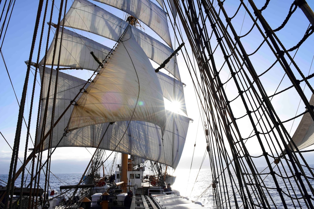 A view from the deck of a ship with sails as it travels through a body of water.