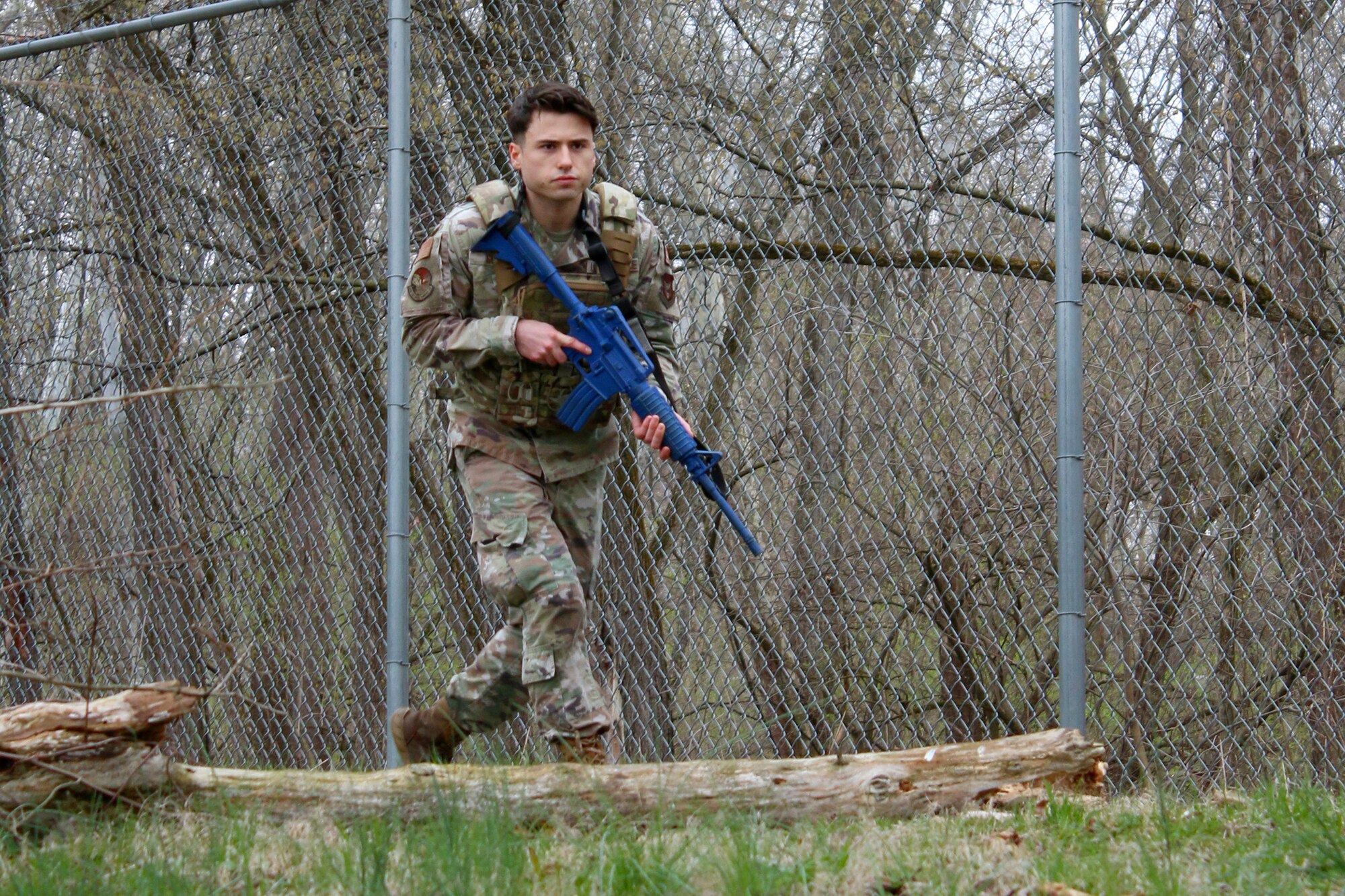 Senior Airman Bristan Guza, a defender from the 445th Security Forces Squadron, skirts a fence line while leading a fire team during field movement training on April 2, 2023. Despite the wet and cold weather, defenders from the 445th practiced skill such as maneuvers, fire teams, formations, cover and concealment, and critical thinking.