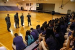 Sailors talk to high school students in an auditorium.
