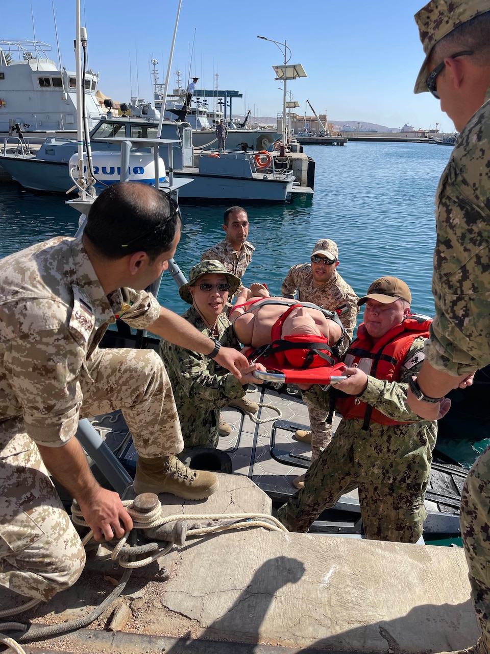 Capt. Jack Tsao, commanding officer of U.S. Navy Central Command’s Navy Reserve medical unit, and Hospital Corpsman Senior Chief Matthew Watton, of NAVCENT’s active staff, with assistance from Jordanian and U.S. service members, carry a simulated medical casualty to shore on March 12, 2023 at the Royal Jordanian Navy Base in Aqaba, Jordan, during International Maritime Exercise/Cutlass Express 2023. IMX/CE 2023 is the largest multinational training event in the Middle East, involving 7,000 personnel from more than 50 nations and international organizations committed to preserving the rules-based international order and strengthening regional maritime security cooperation. (U.S. Navy photo by Lt. Freddie Mawanay)