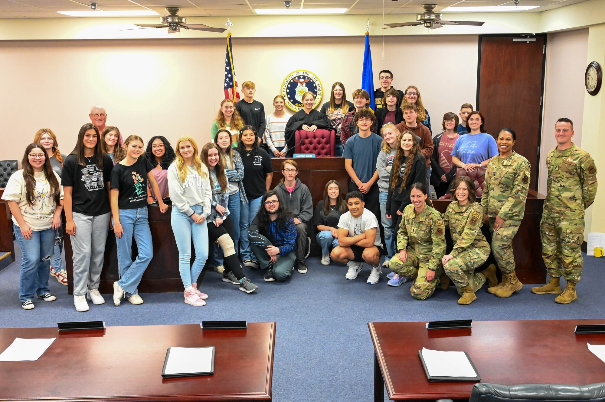 Airmen from the 97th Air Mobility Wing judge advocate office pose for a photo with students and faculty from Altus High School in the courtroom at Altus Air Force Base, Oklahoma, May 1, 2023. The Airmen hosted the mock trial in celebration of National Law Day. (U.S. Air Force photo by Senior Airman Trenton Jancze)