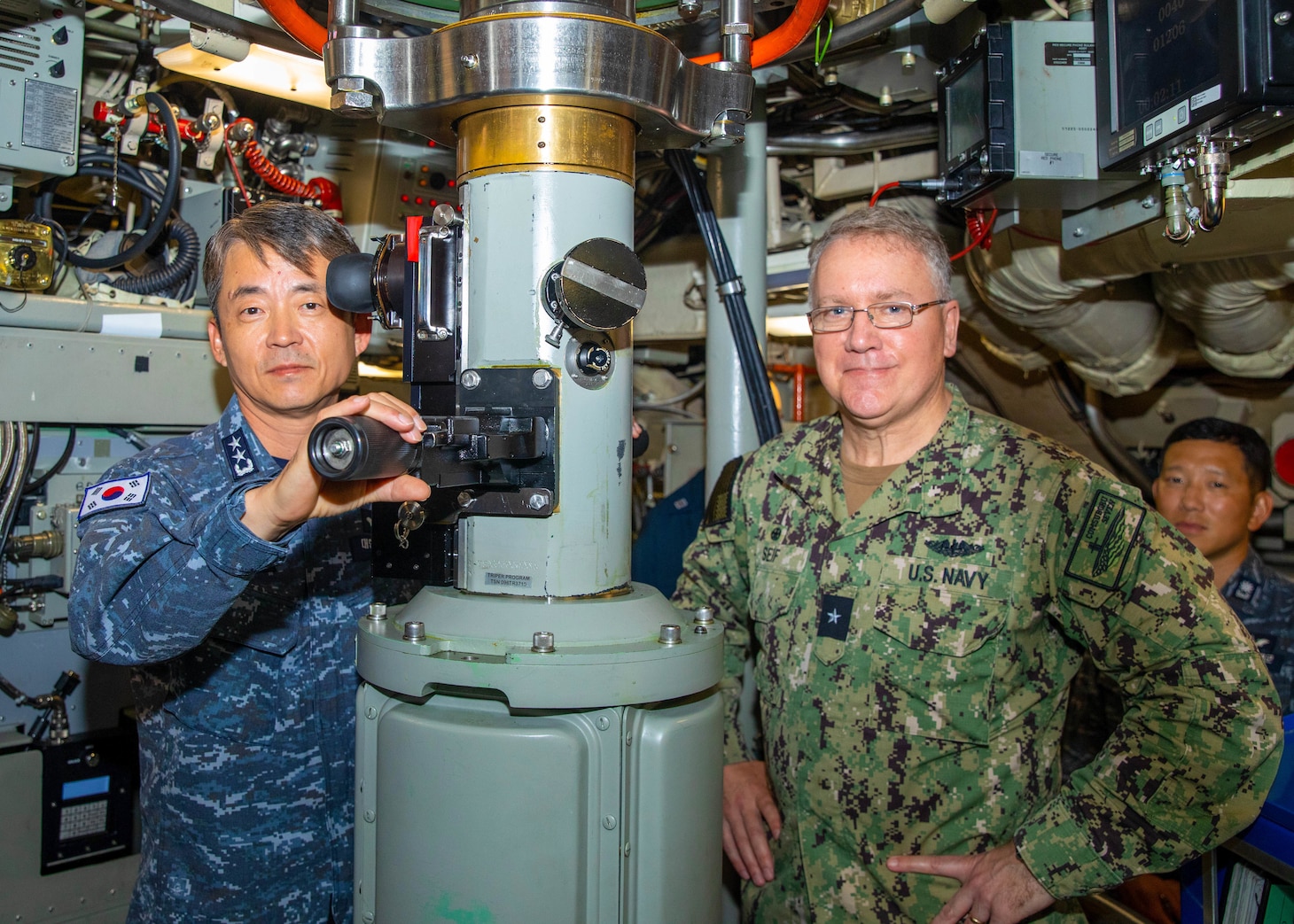 Navy Rear Adm. Su Youl Lee, commander, ROKN Submarine Force, left; poses for a photo with U.S. Navy Rear Adm. Rick Seif, commander, Submarine Group 7; while using the periscope aboard the Ohio-class ballistic missile submarine USS Maine (SSBN 741), April 18.
