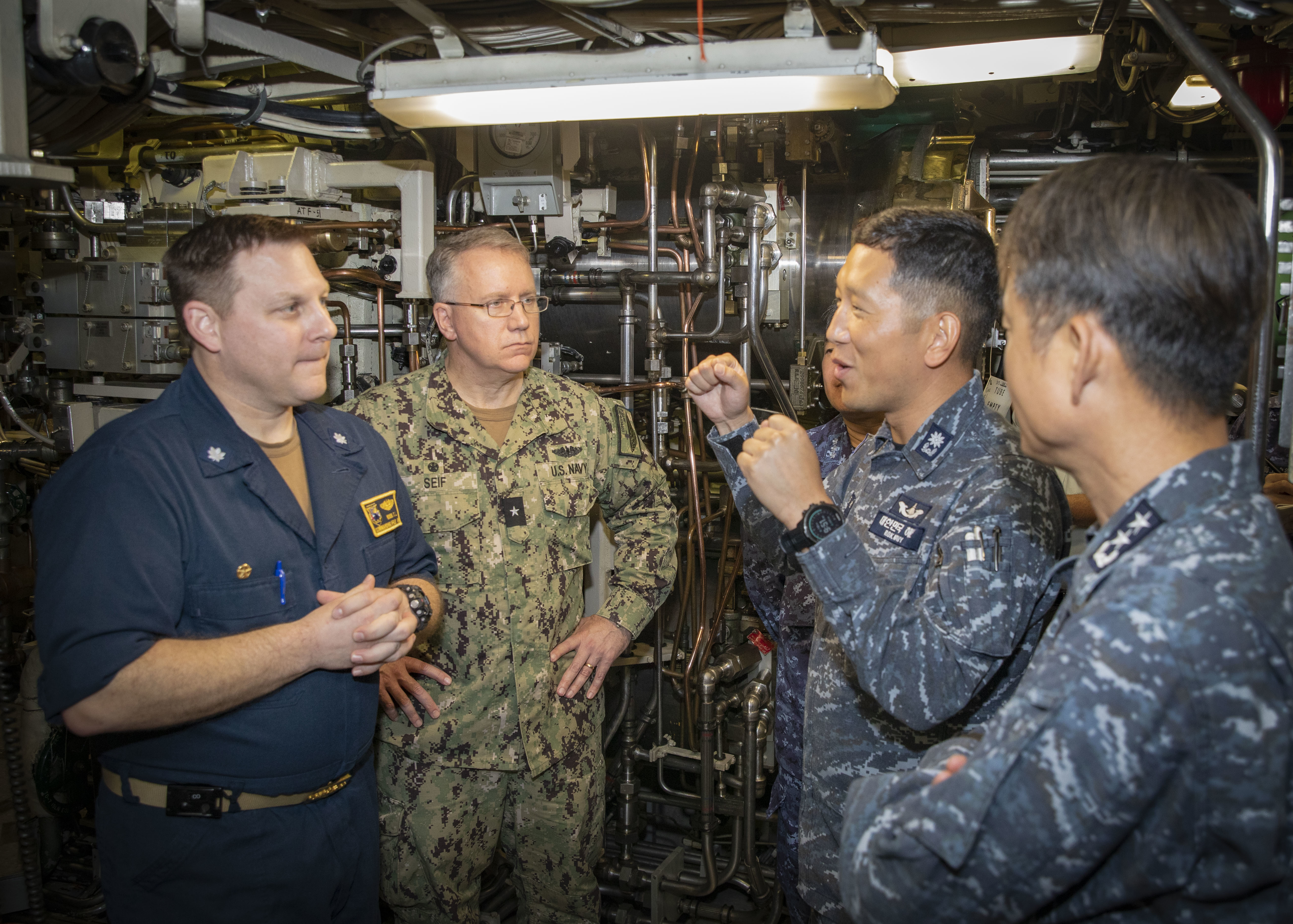 U.S. Navy Cmdr. Travis Wood, commanding officer of Ohio-class ballistic-missile submarine USS Maine (SSBN 741) Gold Crew, left; U.S. Navy Rear Adm. Rick Seif, commander, Submarine Group 7 (second from left); Republic of Korea (ROK) Navy Rear Adm. Su Youl Lee (far right), commander, Submarine Force; and ROK Navy Lt. Cmdr. Dongkeon Oh, executive officer of ROK Navy submarine ROKS SON WON IL (SS-072); hold a conversation aboard Maine, April 18.