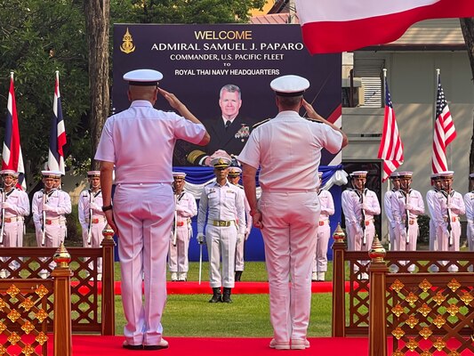 Adm. Suwin Jangyodsuk, left, and Adm. Samuel Paparo, right, salute the Inspection of the Guard of Honor at the Royal Thai Navy Headquarters.