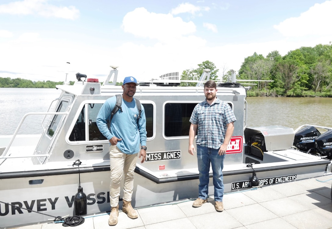 Two men standing by a boat