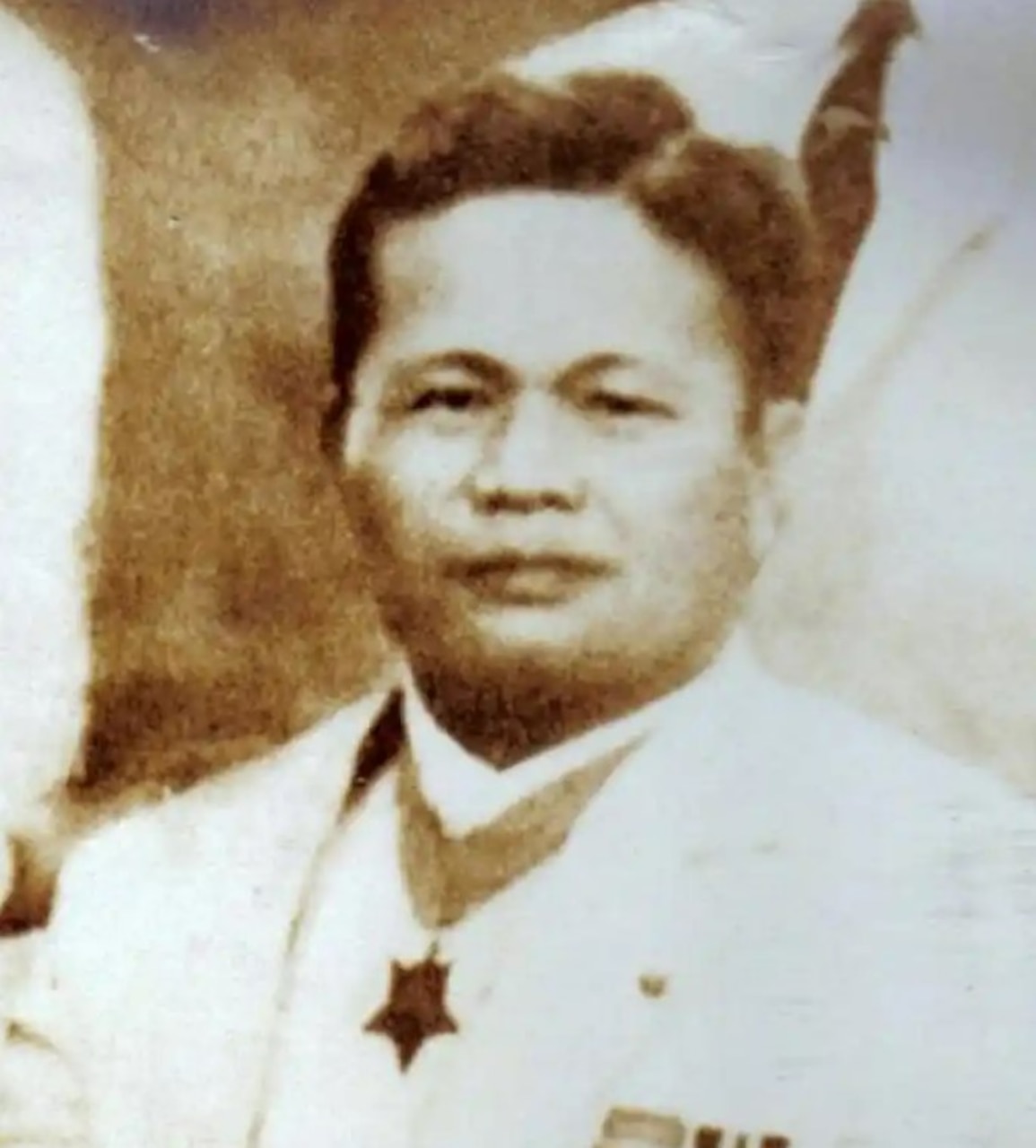 A man poses for a photo while wearing a medal around his neck.