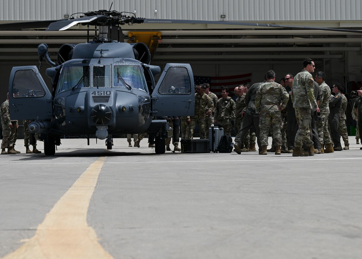 A group of people in military uniforms unload equipment from a helicopter.