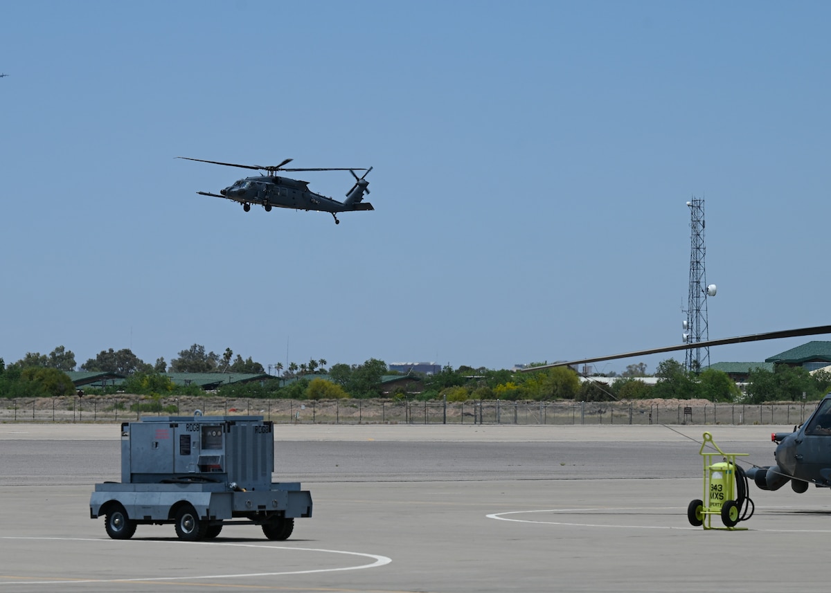 A helicopter lands on a flight line.