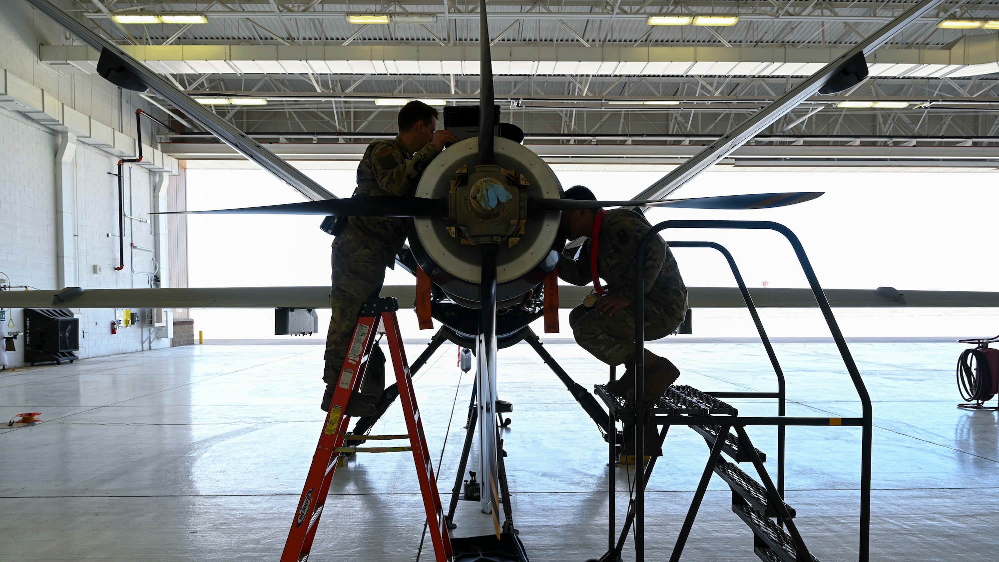 U.S. Air Force Senior Airman Alejandro Thompson, 29th Aircraft Maintenance Unit MQ-9 Reaper dedicated crew chief, left, and U.S. Air Force Staff Sgt. Erandy Rodriguez, 29th AMU avionics technician, inspect the engine of an MQ-9 at Holloman Air Force Base, New Mexico, May 3, 2023.